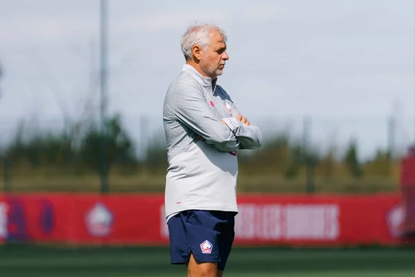 Bruno Genesio après un match, les bras croisés sur le terrain.