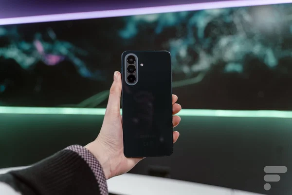 Samsung Galaxy A57 noir tenu en main, avec son module photo arrière et le logo Samsung.