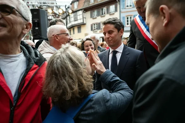 Gabriel Attal échange avec des citoyens lors d'un déplacement.