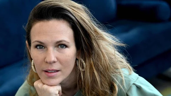 Lorie, le menton sur la main, devant un fond bleu.