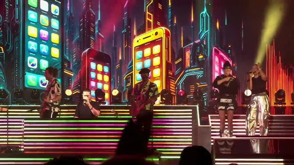 Aqua en concert en 2025 à Copenhague, avec des décors de smartphone géants et une ambiance néon.