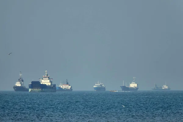 Des navires marchands ancrés dans le détroit d'Ormuz, sous un ciel brumeux.