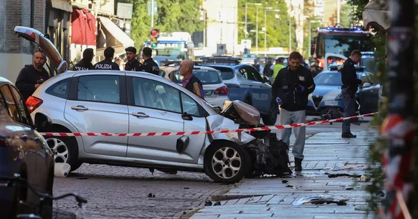 Scène de l'attaque à la voiture bélier à Modène, avec la voiture endommagée et les forces de l'ordre.