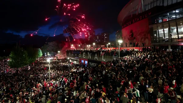 Supporters d'Arsenal rassemblés devant l'Emirates Stadium avec feux d'artifice pour fêter le titre.