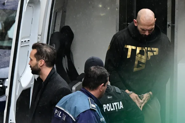 Andrew Tate encadré par la police roumaine lors de son transfert.
