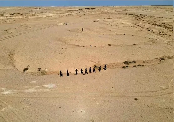 Vue aérienne d'un désert irakien avec un groupe de personnes marchant.