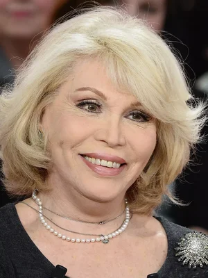 Amanda Lear souriante avec des colliers de perles.