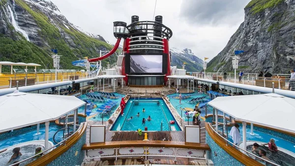 Pont-piscine d'un navire de croisière Disney avec toboggan et écran géant.