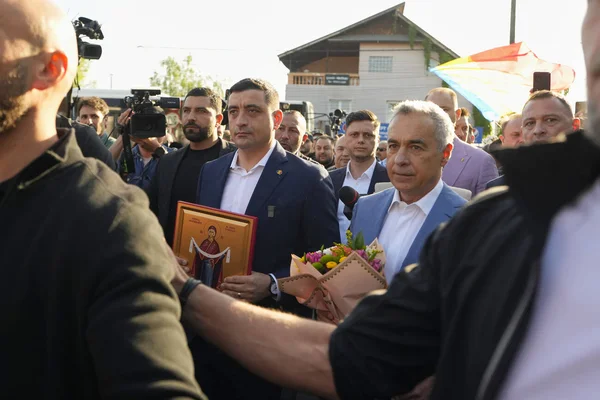 Rassemblement politique en Roumanie, mêlant symboles religieux et drapeau arc-en-ciel, illustrant les tensions sociétales.