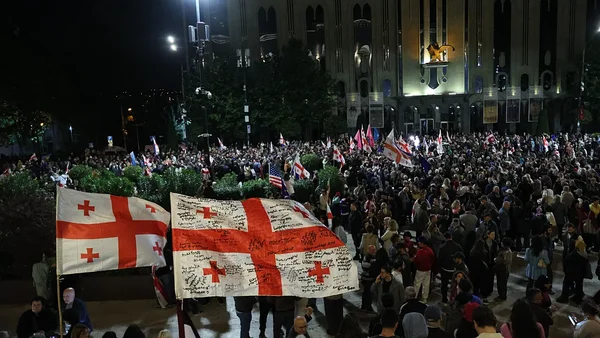 Manifestation pro-UE de nuit devant un bâtiment officiel à Tbilissi, avec des drapeaux géorgiens et américains.