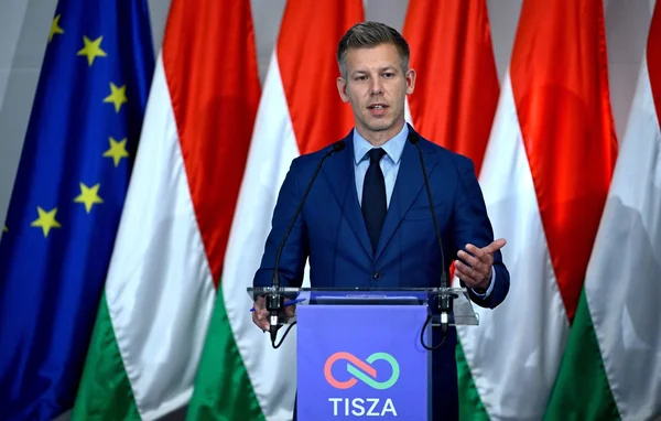 Peter Magyar, nouveau Premier ministre hongrois, derrière un pupitre TISZA, entouré des drapeaux européen et hongrois