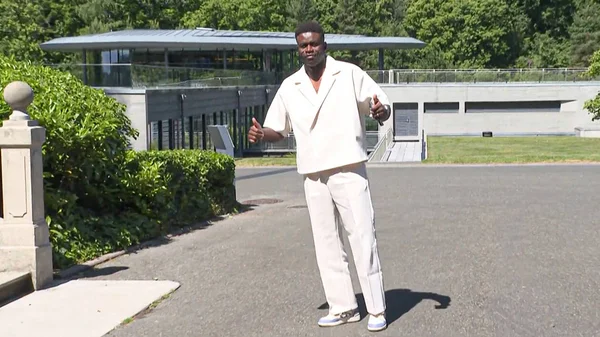 Un joueur des Bleus en tenue blanche immaculée pose devant le bâtiment de Clairefontaine.