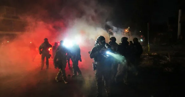 Agents de l'ICE avancent dans une rue de Minneapolis lors d'une opération nocturne tendue.
