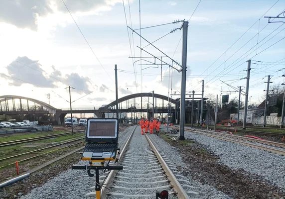 Opérateurs du CDG Express effectuant des relevés techniques sur les voies, avec un appareil de mesure et un ordinateur portable.