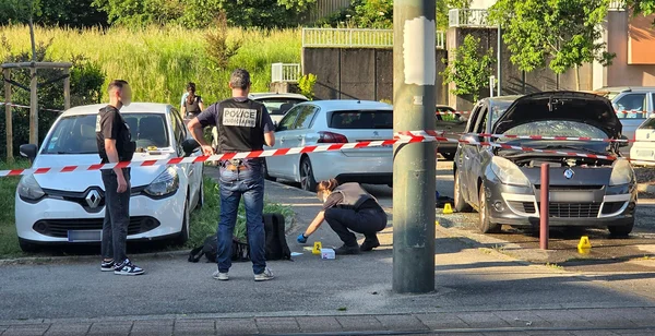 Enquête de police sur une scène de crime, avec ruban de signalisation et véhicules examinés.