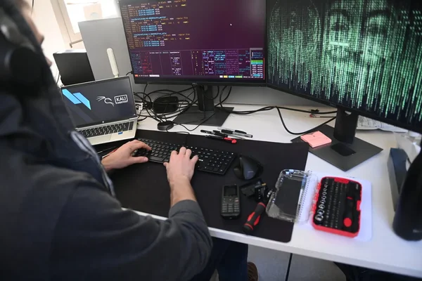 Poste de travail de piratage avec plusieurs écrans affichant du code et des symboles numériques.