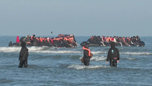 Deux canots surchargés de migrants près du rivage, avec des sauveteurs en combinaison noire dans les vagues, après une panne moteur au large du Pas-de-Calais.