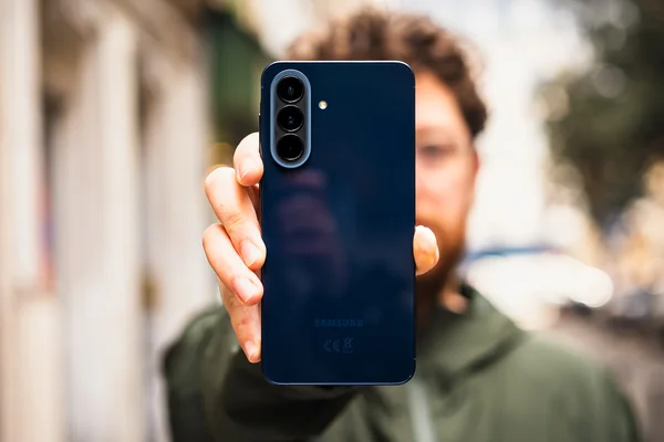Un utilisateur tient le Samsung Galaxy A57 bleu foncé, dévoilant son triple capteur photo.