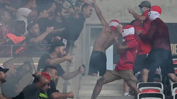 Affrontements entre supporters avant un match, avec des fumigènes.