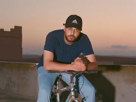 Hakim Jemili posant avec un vélo au coucher du soleil, lors d'une séance photo.