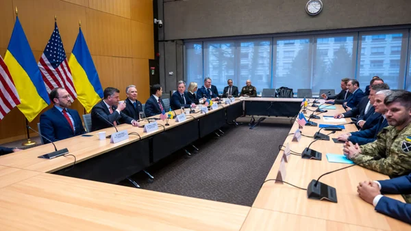 Réunion de négociation autour d'une table de conférence avec drapeaux ukrainiens et américain.