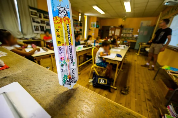 Thermomètre affichant 30°C dans une salle de classe pendant la canicule.