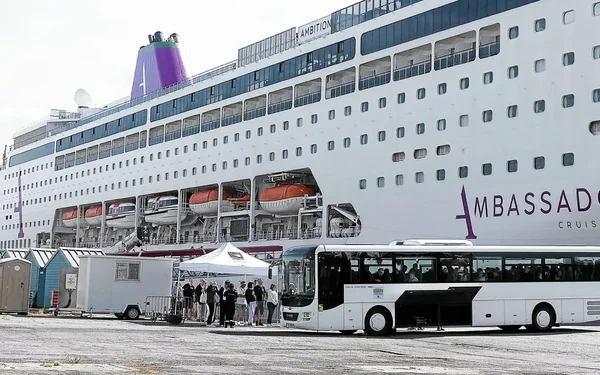 Le paquebot Ambition (Ambassadeur) à quai à Brest, avec un bus et un chapiteau au premier plan.