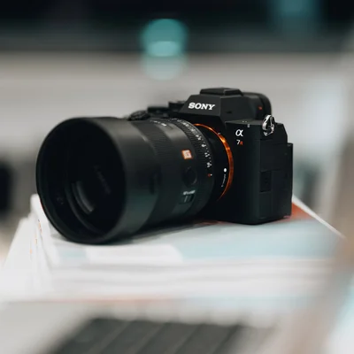 Sony Alpha 7R VI avec objectif, sur une pile de documents.