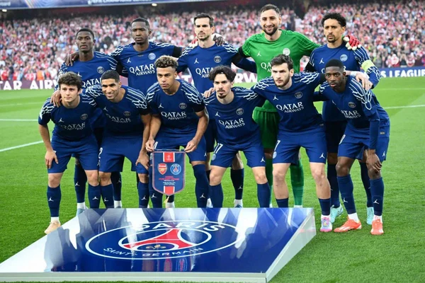 Photo d'équipe des joueurs du PSG en maillot bleu, avec un fanion aux couleurs du PSG et d'Arsenal.