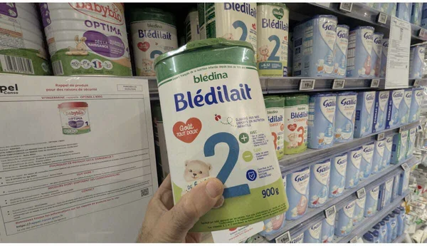 Rayon de laits infantiles en supermarché, avec une boîte de Blédilait en premier plan et un avis de rappel de produit à gauche.
