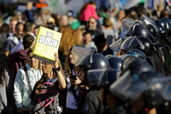 Manifestants face aux forces de l'ordre, une pancarte 'EL FUTURO' brandie au premier plan.