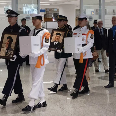 Défilé militaire à Séoul pour le rapatriement des corps de deux vétérans français, avec portraits et urnes.