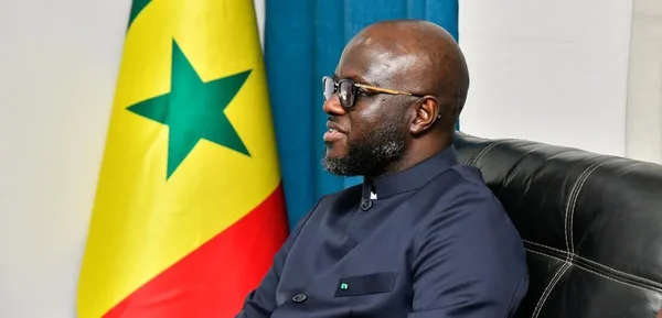El Malick Ndiaye lors d'une rencontre officielle, avec le drapeau du Ghana en arrière-plan.