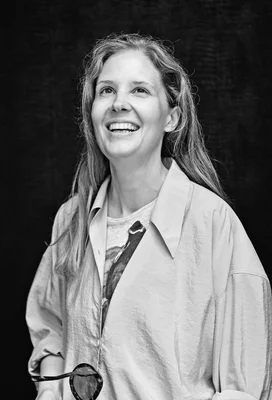Justine Triet, cinéaste, en portrait noir et blanc souriant.