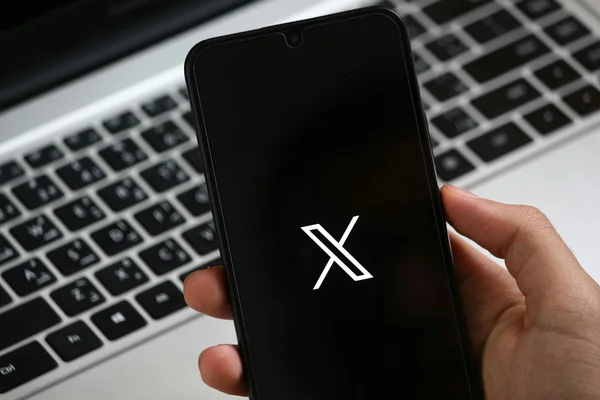 Un smartphone affichant le logo de X, utilisé dans un contexte professionnel.