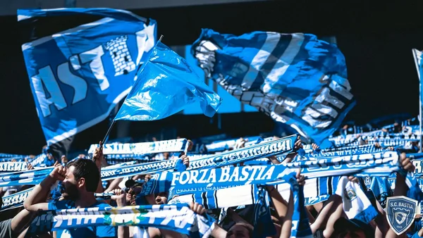 Supporters bastiais en déplacement à Bordeaux, affichant leur soutien avec des drapeaux et écharpes aux couleurs du club.