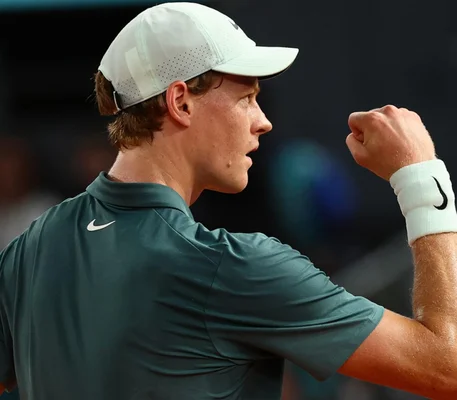 Jannik Sinner célébrant un point, le poing levé, sur le court de tennis.
