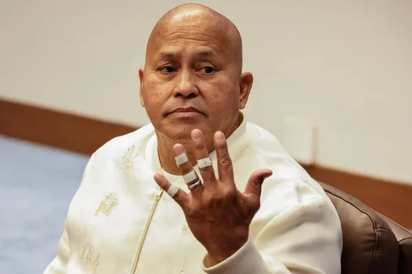 Le sénateur philippin Ronald dela Rosa, en veste blanche brodée, fait un geste avec ses doigts bandés.