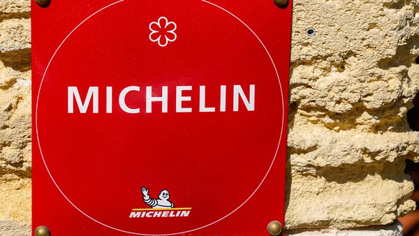 Panneau du Guide Michelin apposé sur un mur en pierre.