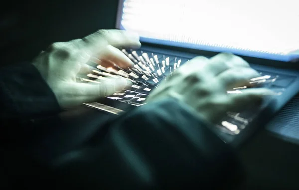 Mains tapant sur un clavier d'ordinateur dans l'obscurité, suggérant une activité de piratage rapide.