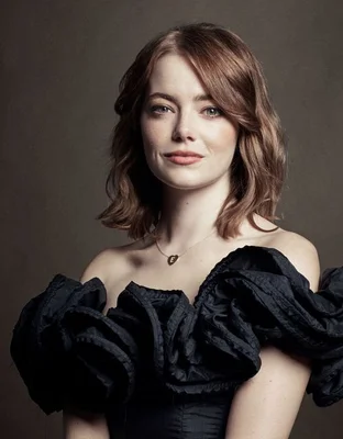 Emma Stone en robe noire et collier doré, portrait de profil.