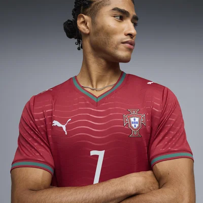 Cristiano Ronaldo en maillot domicile rouge du Portugal (numéro 7, logo Puma), cheveux tressés, photographié en studio.