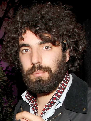 Le réalisateur Romain Gavras, arborant une barbe et des cheveux bouclés, vêtu d'une chemise à motifs rouge et noir.