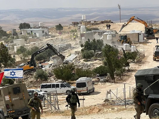 Démolition de propriétés palestiniennes par Israël, avec présence de personnel armé et d'un drapeau israélien.