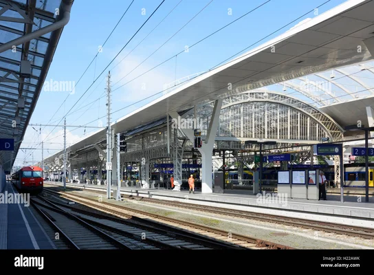 Intérieur de la gare centrale de Salzbourg avec une locomotive rouge et des agents en tenue de sécurité.