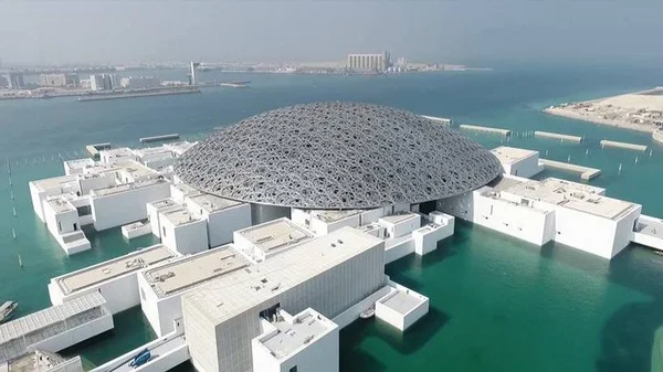 Vue aérienne du Louvre Abu Dhabi sur l'île de Saadiyat, avec son dôme emblématique et son architecture distinctive.