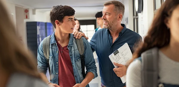 Un enseignant s'entretient avec un élève dans un couloir d'école.