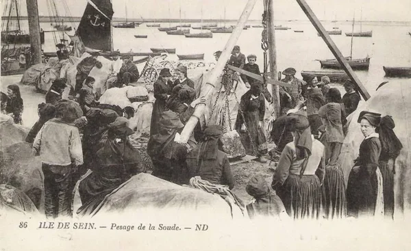 Scène de port historique sur l'île de Sein au début du XXe siècle, habitants en costumes traditionnels.
