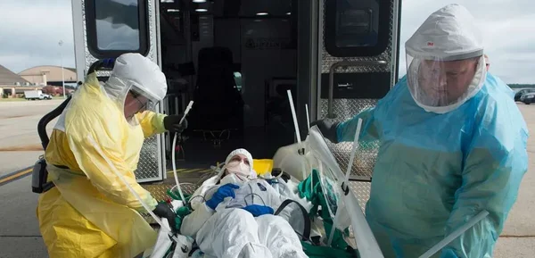 Transfert d'un patient suspecté d'Ebola vers une ambulance par du personnel médical en tenue de protection.