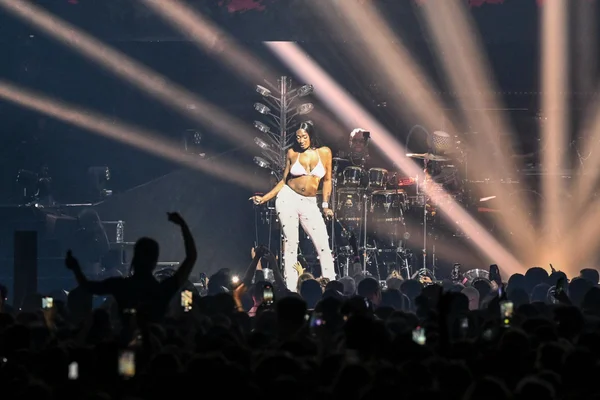 Aya Nakamura en concert, entourée de son groupe et d'une foule de fans.
